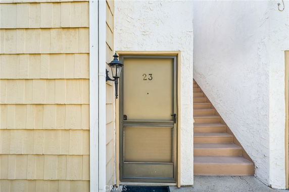 Front view of an entrance with a staircase and door numbered 23.