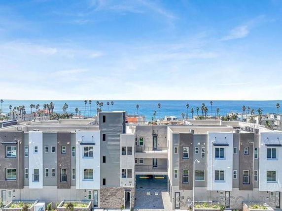 Front view of a modern multi-story building with ocean in the background.