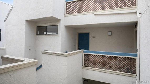 Exterior view of a multi-story building with a blue door and lattice-style railings.