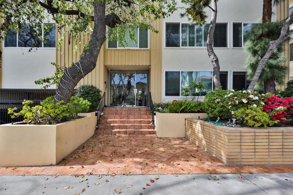 Front view of a building entrance with stairs and landscaping.