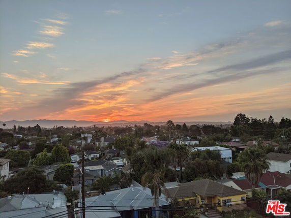 Panoramic view of a neighborhood with houses and trees, set against a sunset sky.