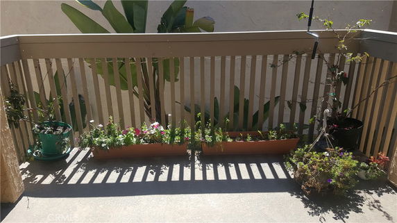 Small outdoor patio area with potted plants and a wooden railing.