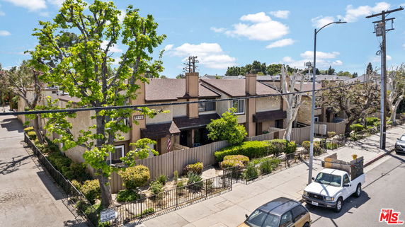 Front view of a multi-story residential building with a fenced garden.