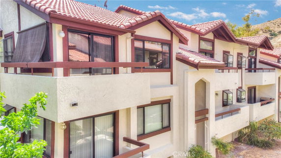 Front view of a multi-story building with balconies and red tile roofing.