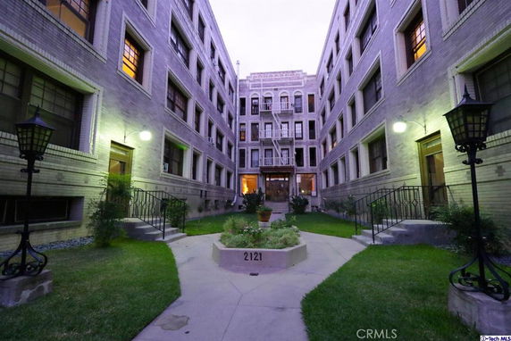 Front view of a multi-story apartment building with entrance courtyard.