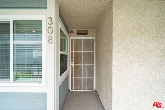 Front view of a house entrance with a metal security door and window with blinds.