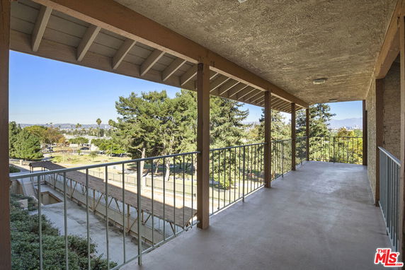 View from a building balcony overlooking tree-lined surroundings.
