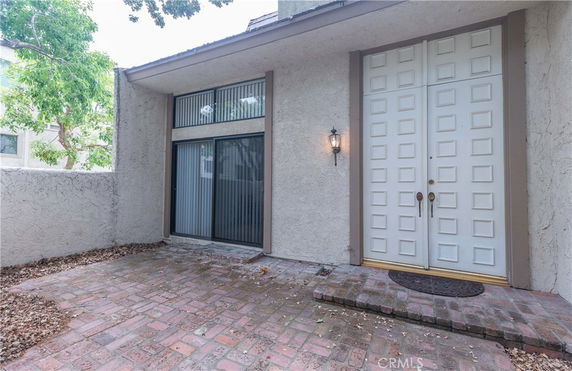 Front view of a house with a double door entrance and brick patio.