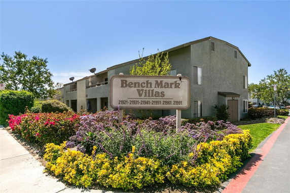 Front view of a multi-story apartment building with a sign for Bench Mark Villas.