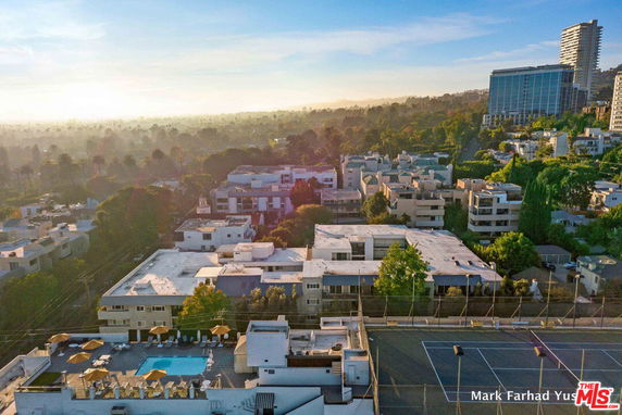 Wide-angle view of residential buildings with a rooftop pool and tennis court.