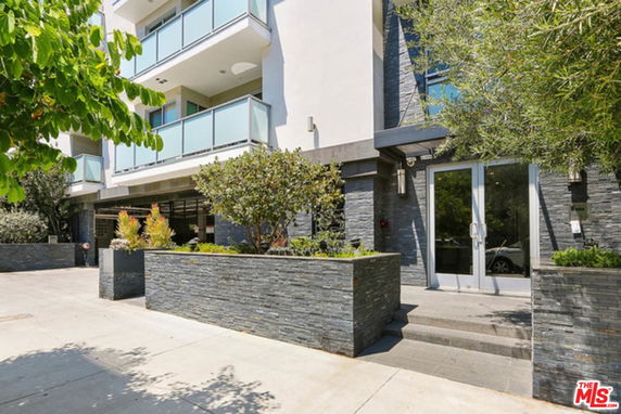 Front view of a modern multi-story building with balconies and stone accents.