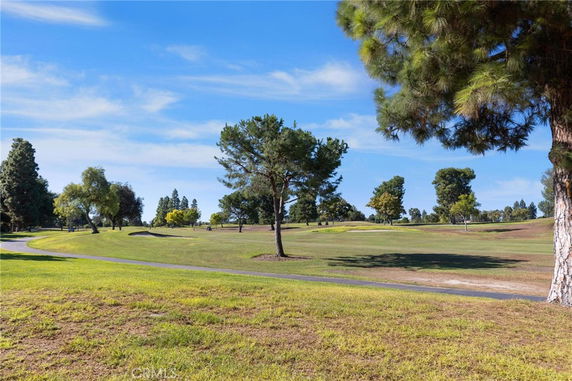 Scenic view of a park or golf course with trees and a clear sky.