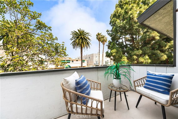 Patio area with seating, overlooking trees and buildings.