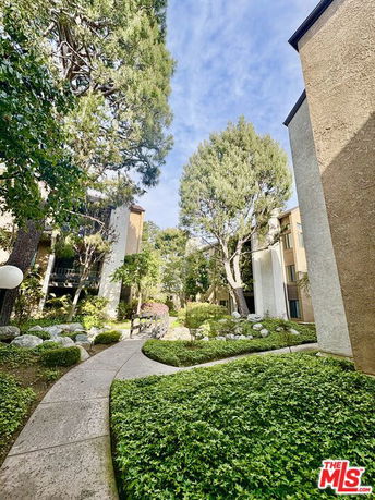 Pathway with surrounding greenery between apartment buildings.