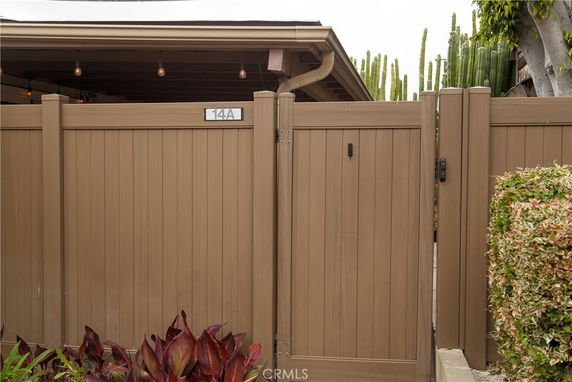 Front view of a gated entrance to a house with wooden panel fencing.