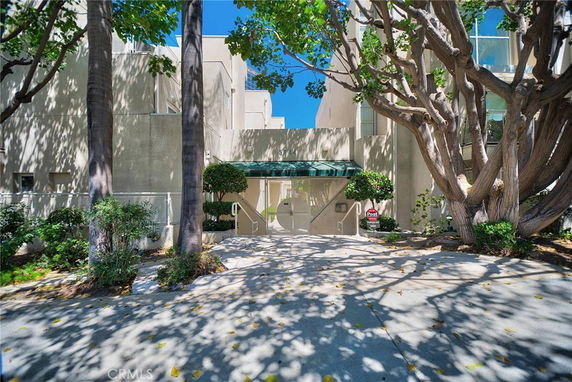 Front view of a modern multi-story building with trees in the foreground