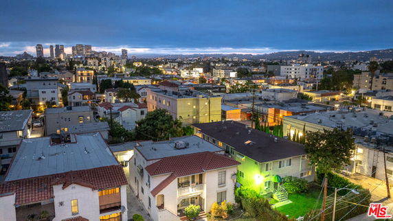 Aerial view of a residential area with multiple buildings and a city skyline in the background.