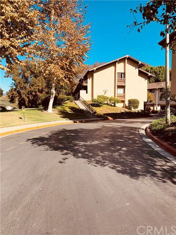 Front view of a multi-story residential building with trees and a pathway.