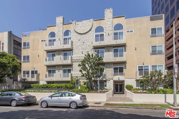Front view of a multi-story apartment building with balconies and arched windows.