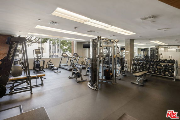 Gym area with exercise equipment, weights, and mirrors.