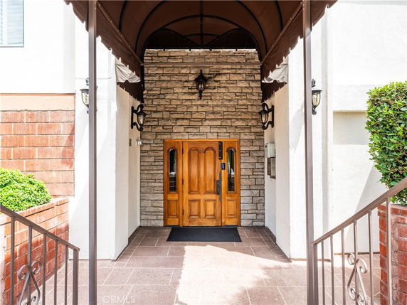 Front entrance of a building with a wooden door and stone wall.