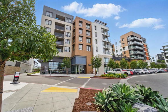 Front view of a modern multi-story apartment building with balconies.