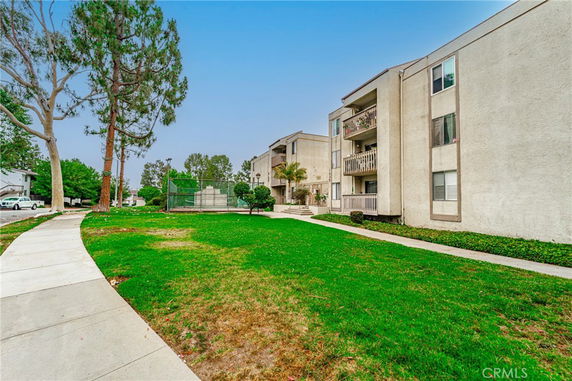 Front view of a multi-story apartment building with balconies and surrounding greenery.