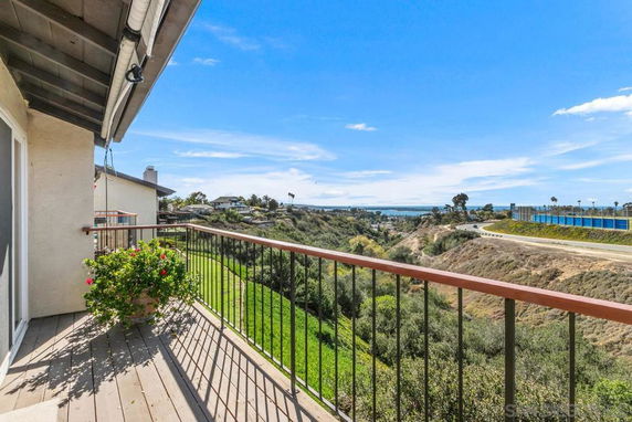 A balcony with a view of hills and a distant ocean.