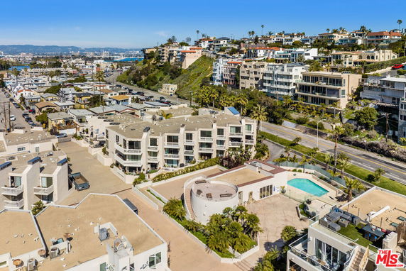 Overhead view of residential buildings with swimming pool and surrounding landscape.
