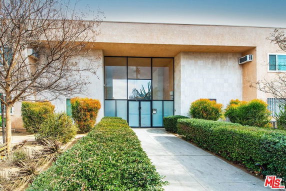 Front view of a building with large glass entrance and landscaped path.