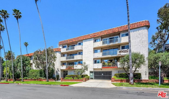 Front view of a multi-story residential building with balconies and a gated entrance.