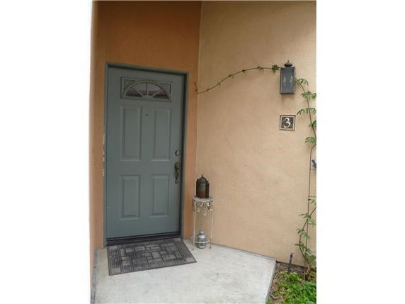 Front view of a house entry with a closed blue door and wall-mounted light.