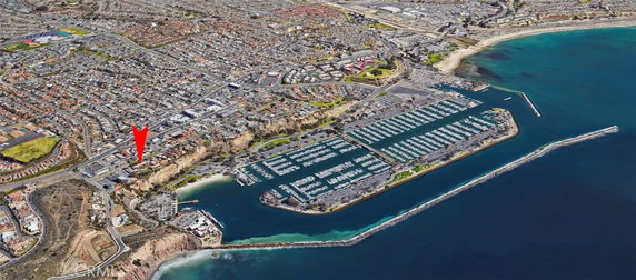 Aerial panoramic view of a coastal cityscape with marina and breakwater.