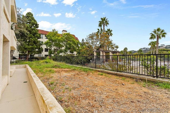 Exterior view with a dry patch of grass and surrounding greenery.