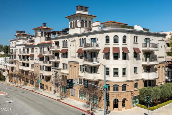 Front view of a multi-story residential building with balconies and awnings.