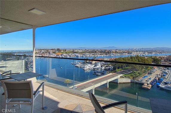 Panoramic view from a balcony overlooking a waterway with boats and a distant city skyline.