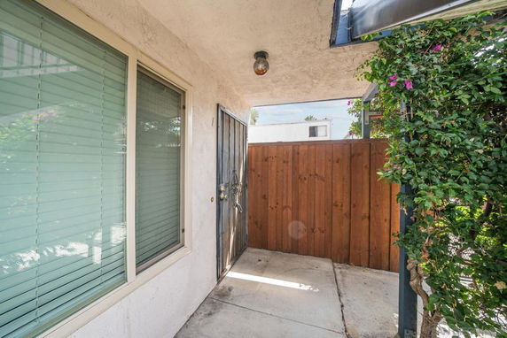 Front view of a house entrance with a metal door and a wooden fence.