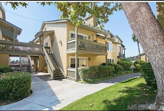 Front view of a two-story residential building with balconies and outdoor staircases.