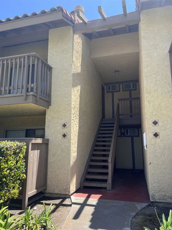 Front view of a two-story house with an exterior staircase and small balconies.
