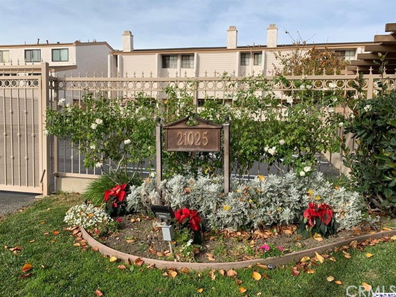 Front view of a residential building with a decorative fence and address sign.