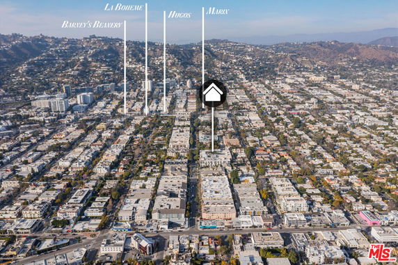 Panoramic aerial view of an urban area with numerous buildings and a hilly background.