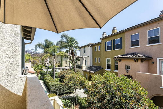View of neighboring multi-story houses and palm trees under an umbrella.