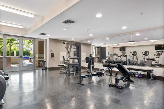 Interior view of a workout gym with various exercise equipment and large mirrors.