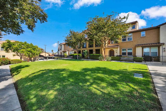 Front view of a multi-story residential building with trees and a grassy area in front.
