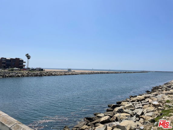 Wide-angle view of a coastal area with water, rocks, and a distant shoreline.