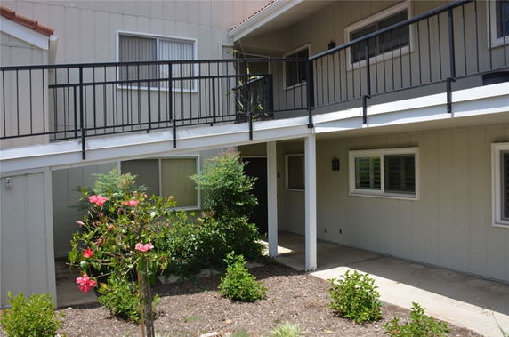 Front view of a two-story building with a balcony and garden area.