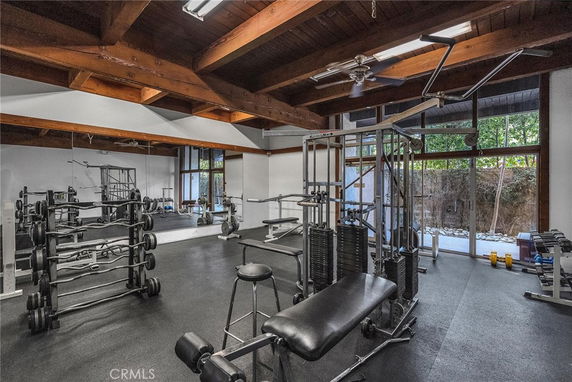 Indoor gym area with various exercise equipment and wooden ceiling beams.