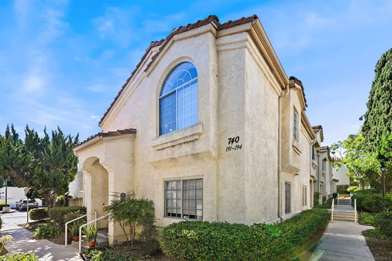 Front view of a multi-story building with arched windows and stucco exterior.