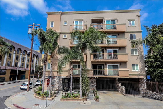 Front view of a multi-story residential building with balconies and a gated entrance.
