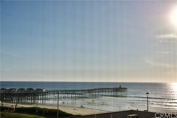 Panoramic view of a pier extending into the ocean with a clear sky.